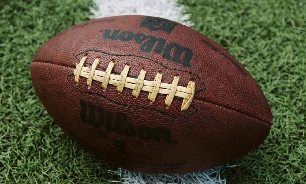 American football lying on white line on field