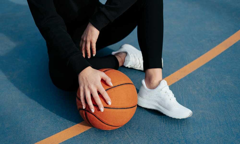 Person sitting on basketball court with basketball