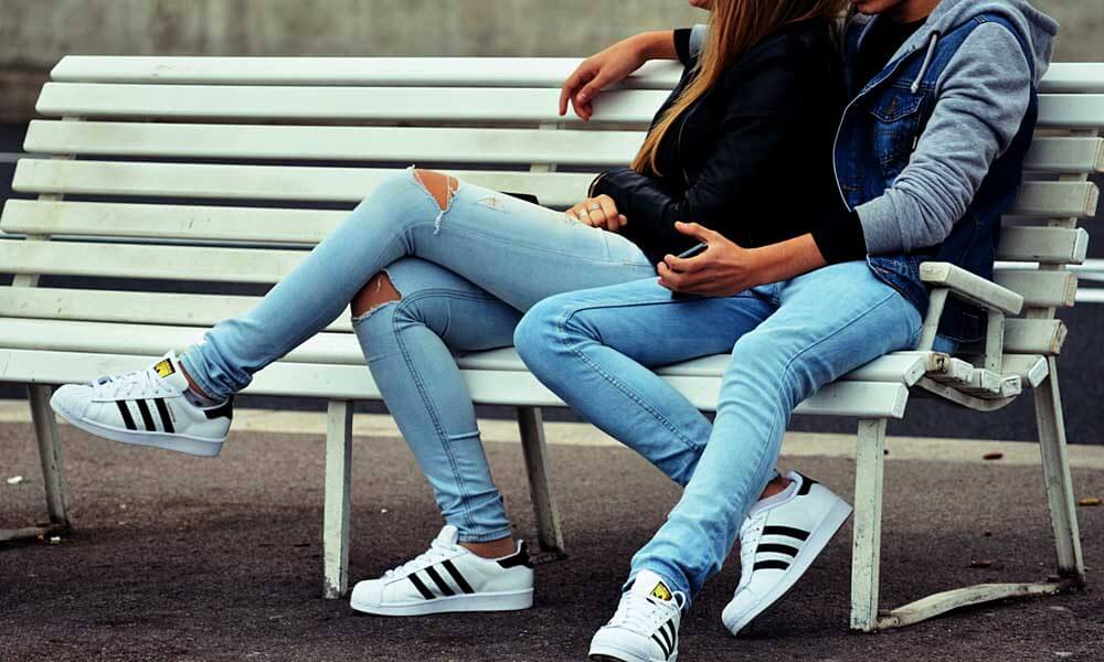 Couple sitting on a bench wearing Adidas shoes