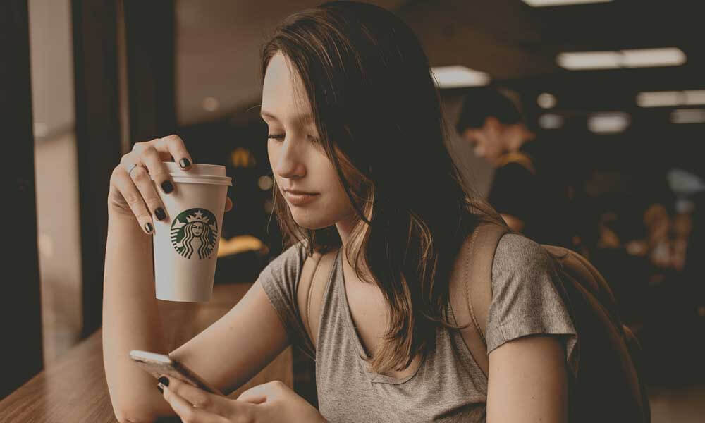 Girl drinking Starbucks coffee and browsing mobile phone