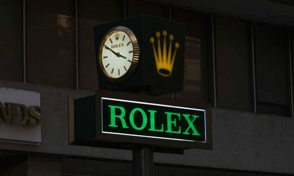 Rolex sign and clock in front of a store with crown logo at night