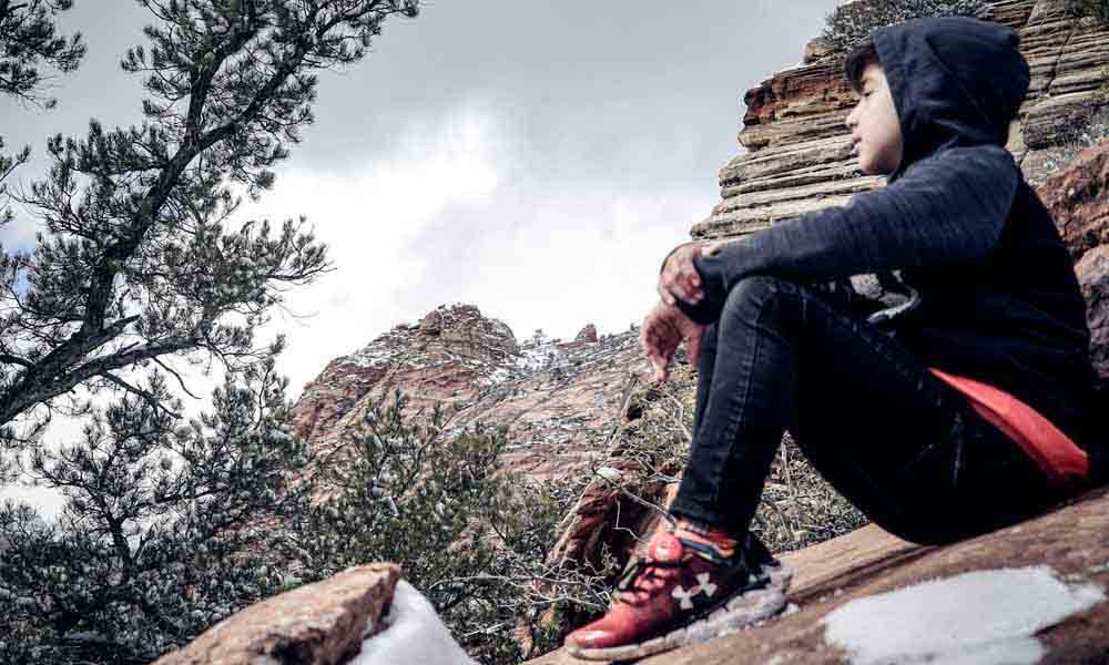 Boy sitting on rock wearing Under Armour shoes
